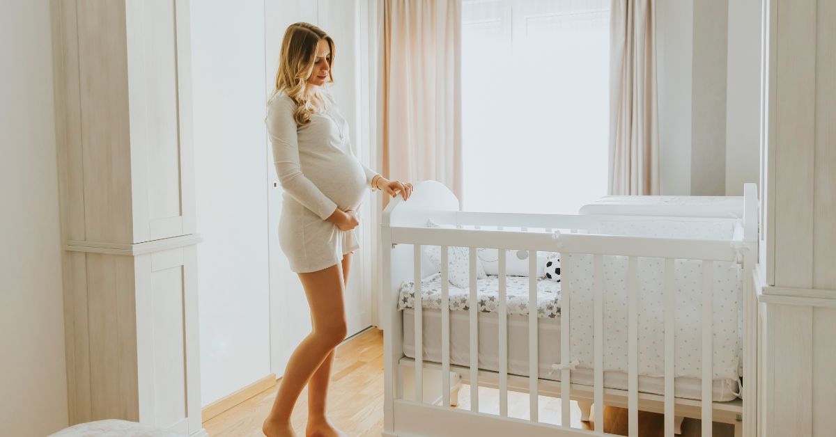 Gravid kommende mor står ved en tremmeseng